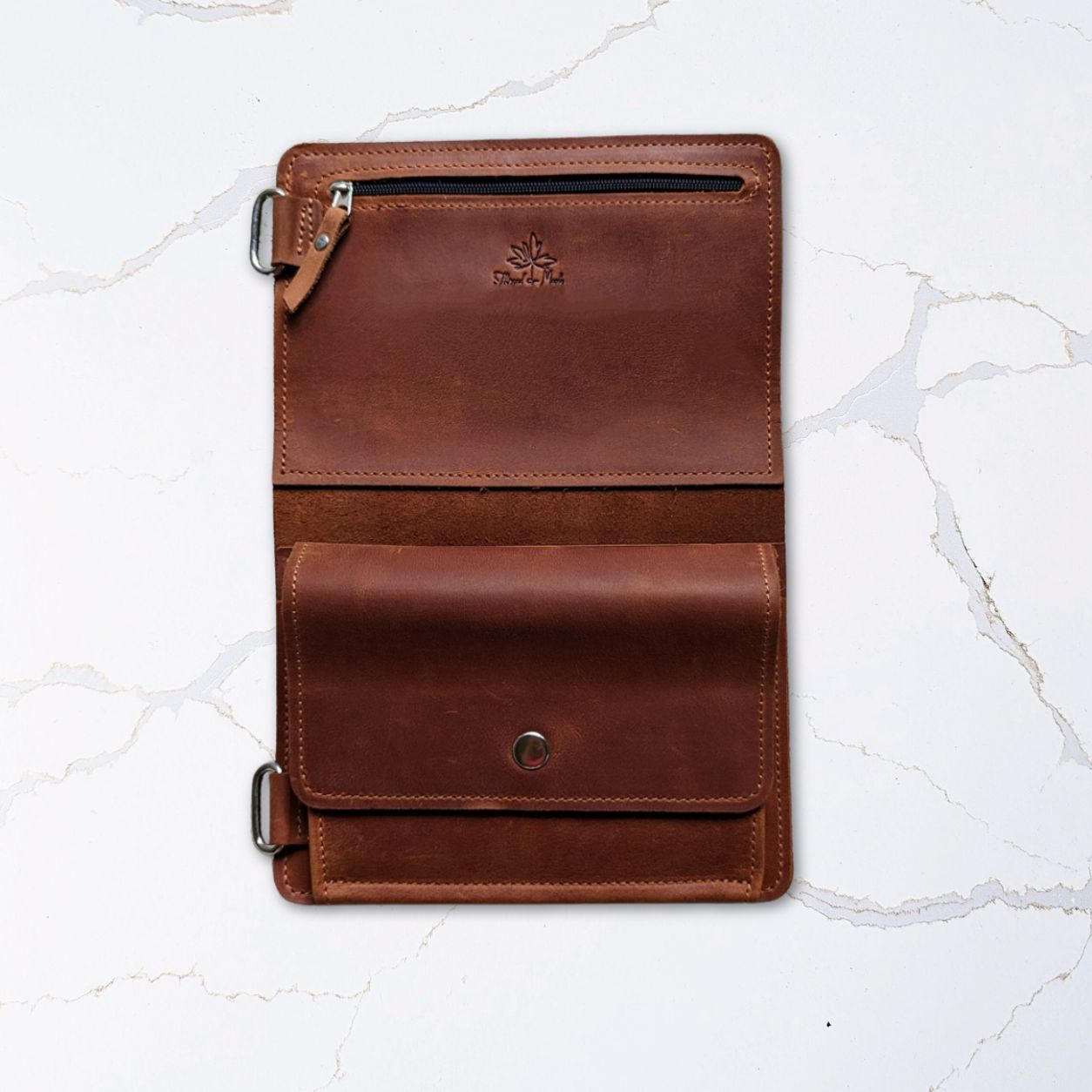Open brown leather wallet on marble surface showing multiple compartments