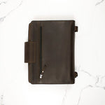 Dark brown leather zippered portfolio on a white marble surface.
