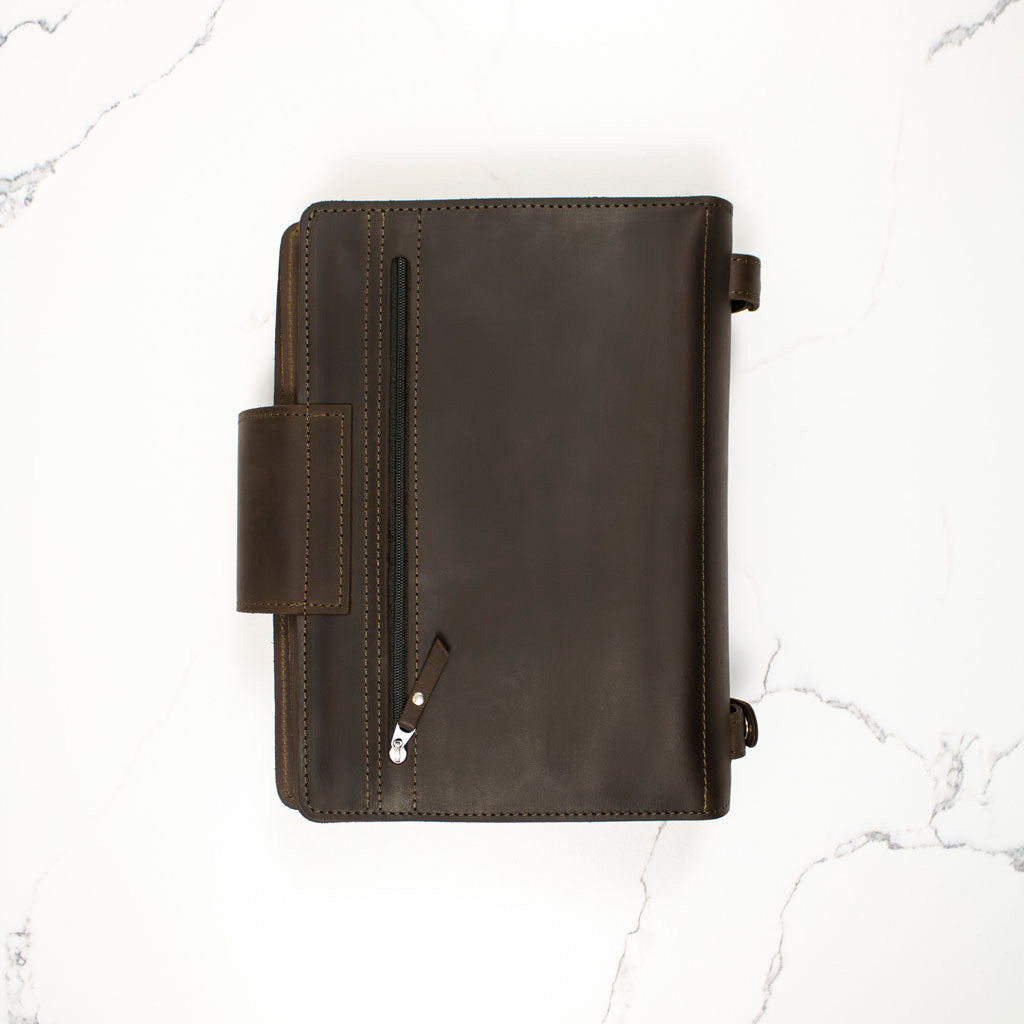 Dark brown leather zippered portfolio on a white marble surface.
