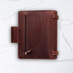 Brown leather portfolio folder with zipper pocket on white marble background