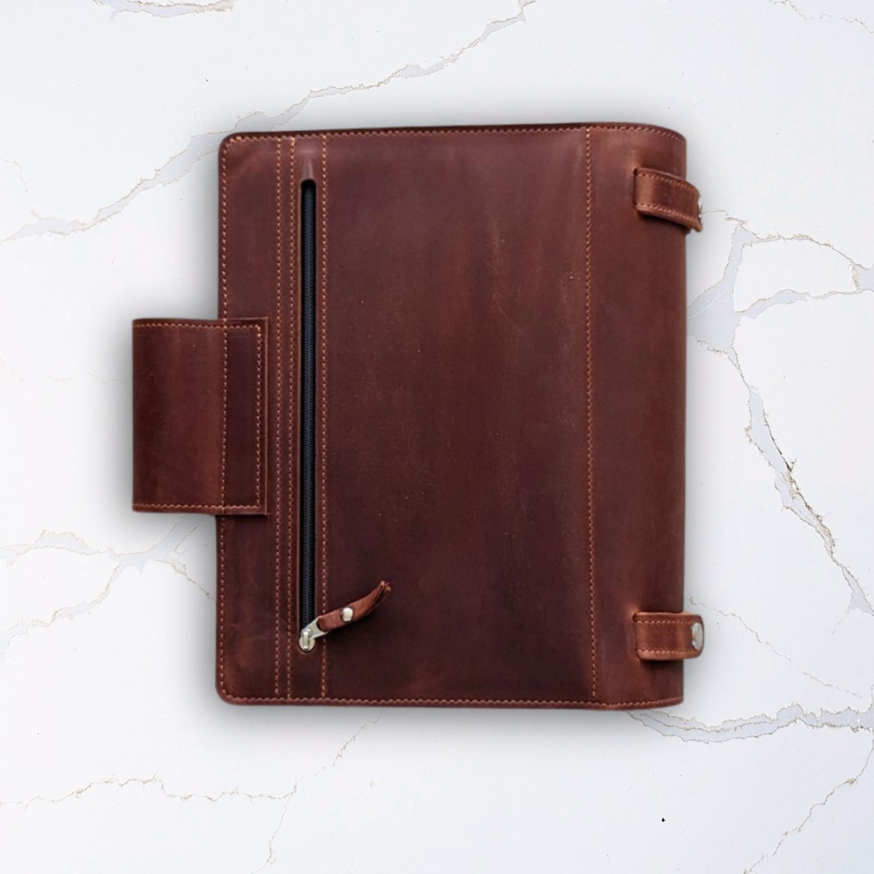 Brown leather portfolio folder with zipper pocket on white marble background