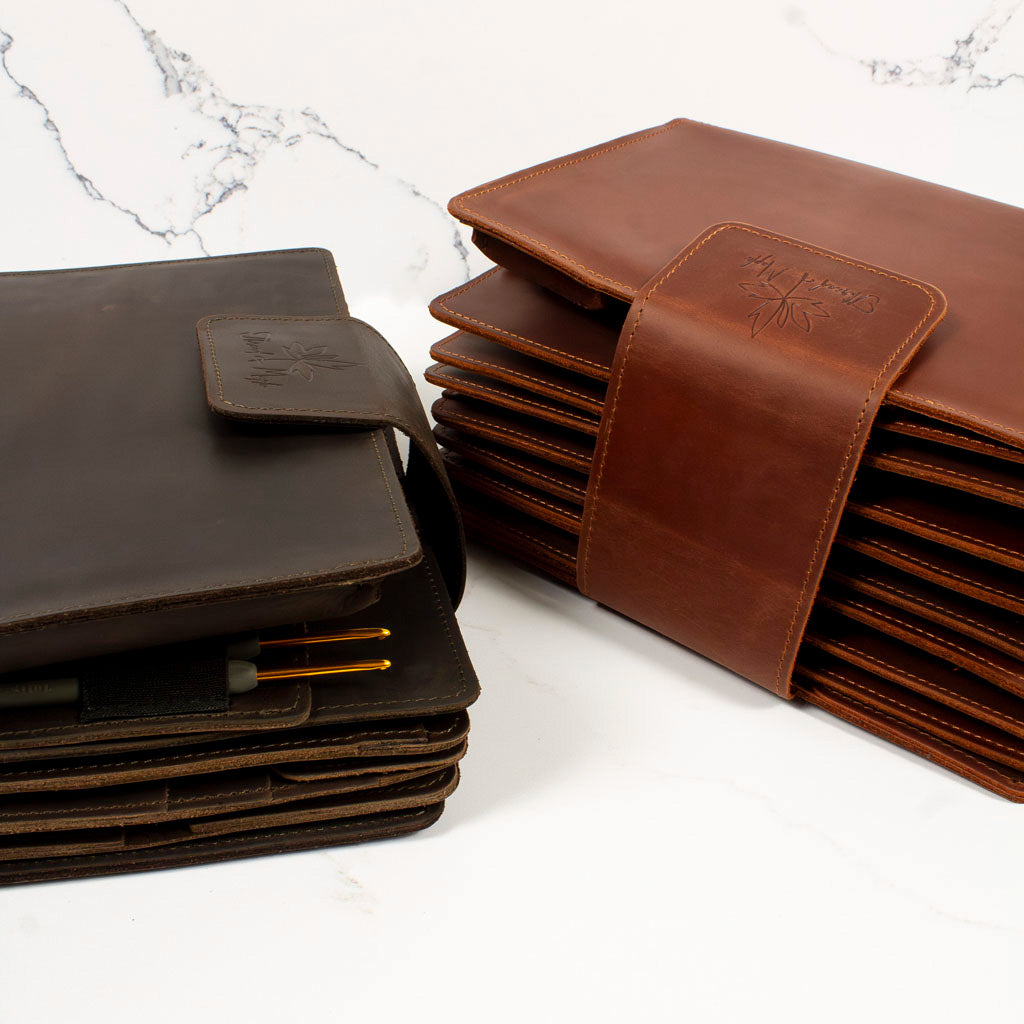 Brown and black leather document holders on a white marble surface.