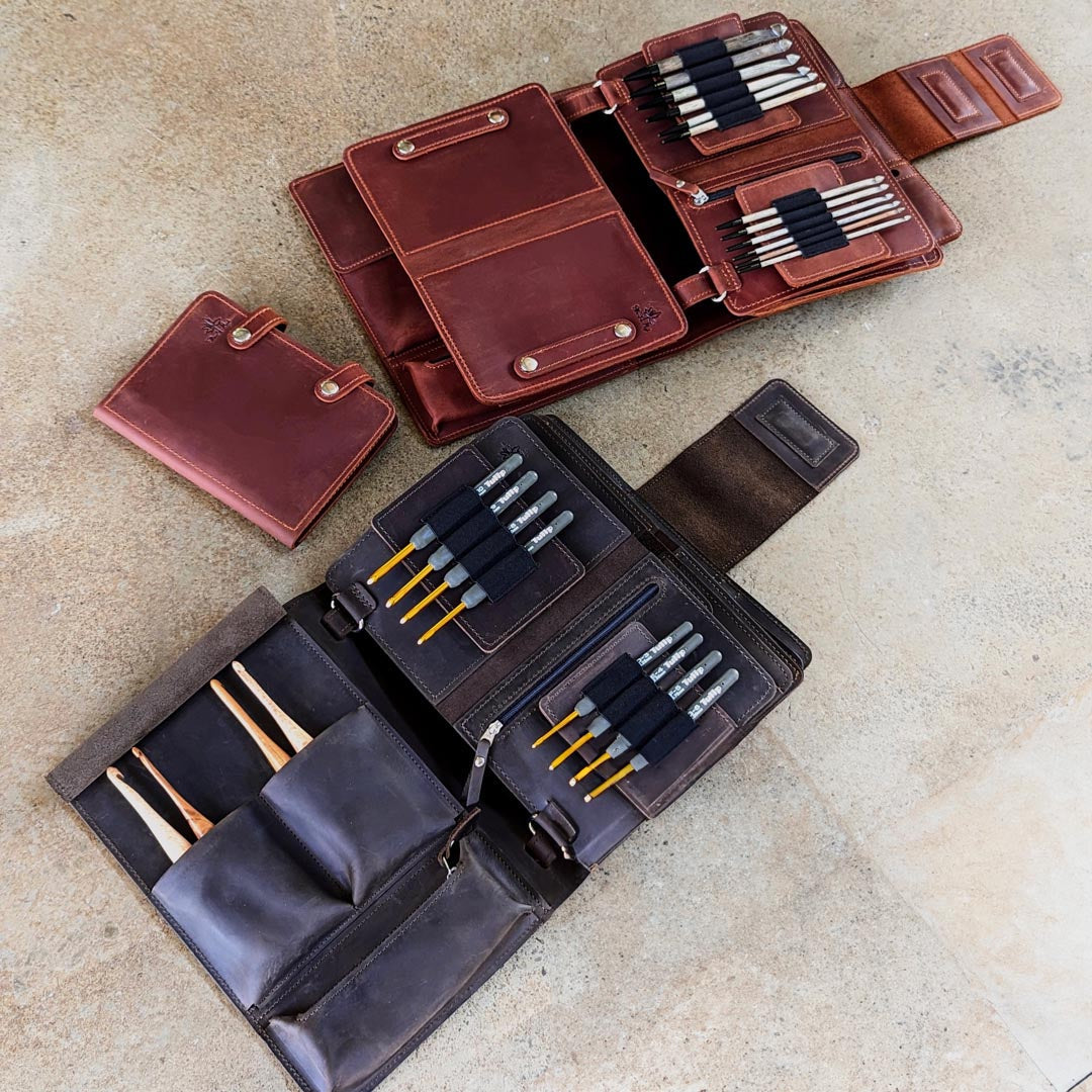 Leather notebook and pen holders laid out on a beige surface with various compartments featuring different colors and sizes.