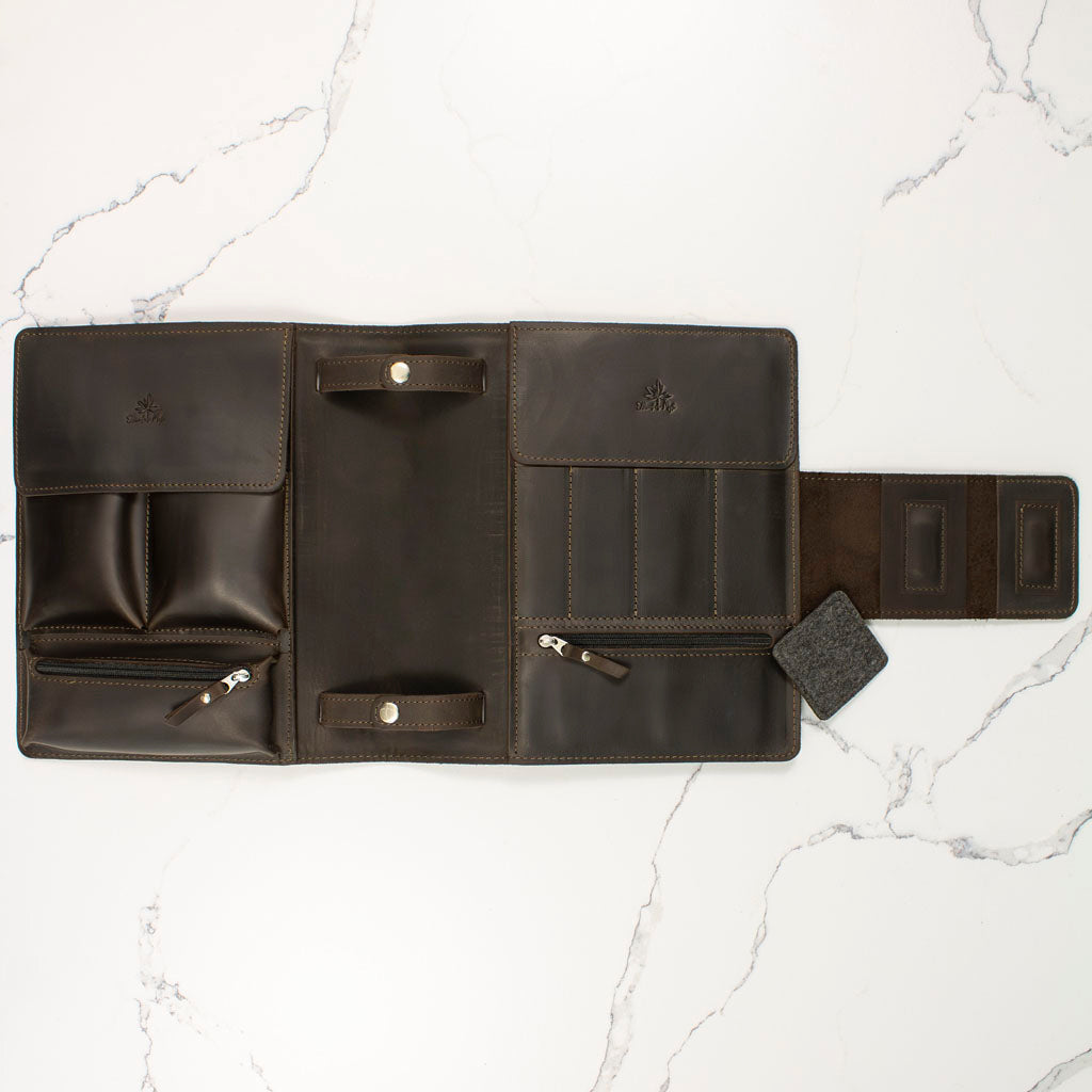 open leather tool roll with multiple pockets and flaps on a marble surface
