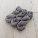 Four skeins of gray yarn neatly arranged on a wooden surface.