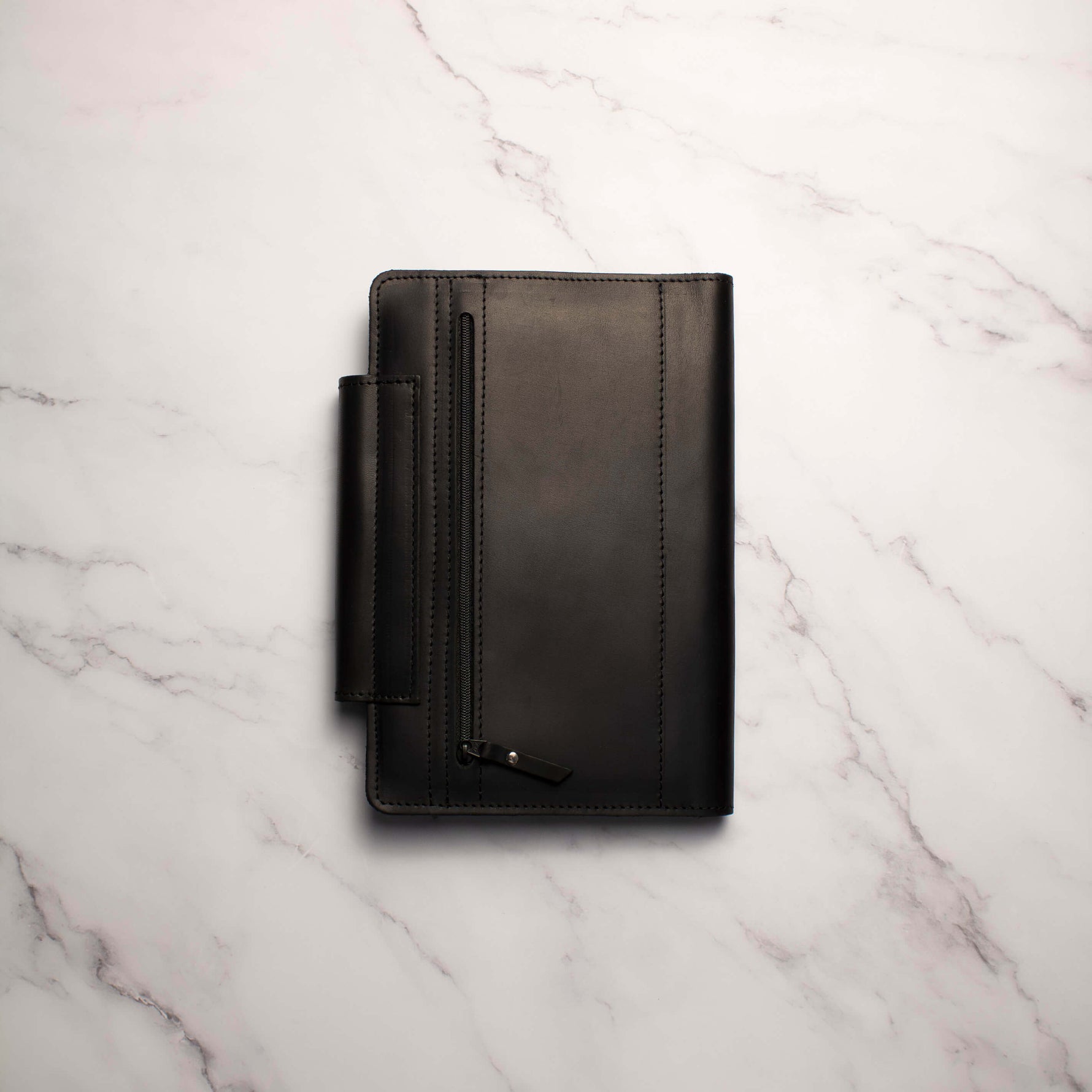 Black leather wallet with zipper on white marble background.