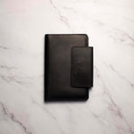 Black leather wallet on a marble surface.