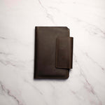 Dark brown leather notebook on a marbled white surface.
