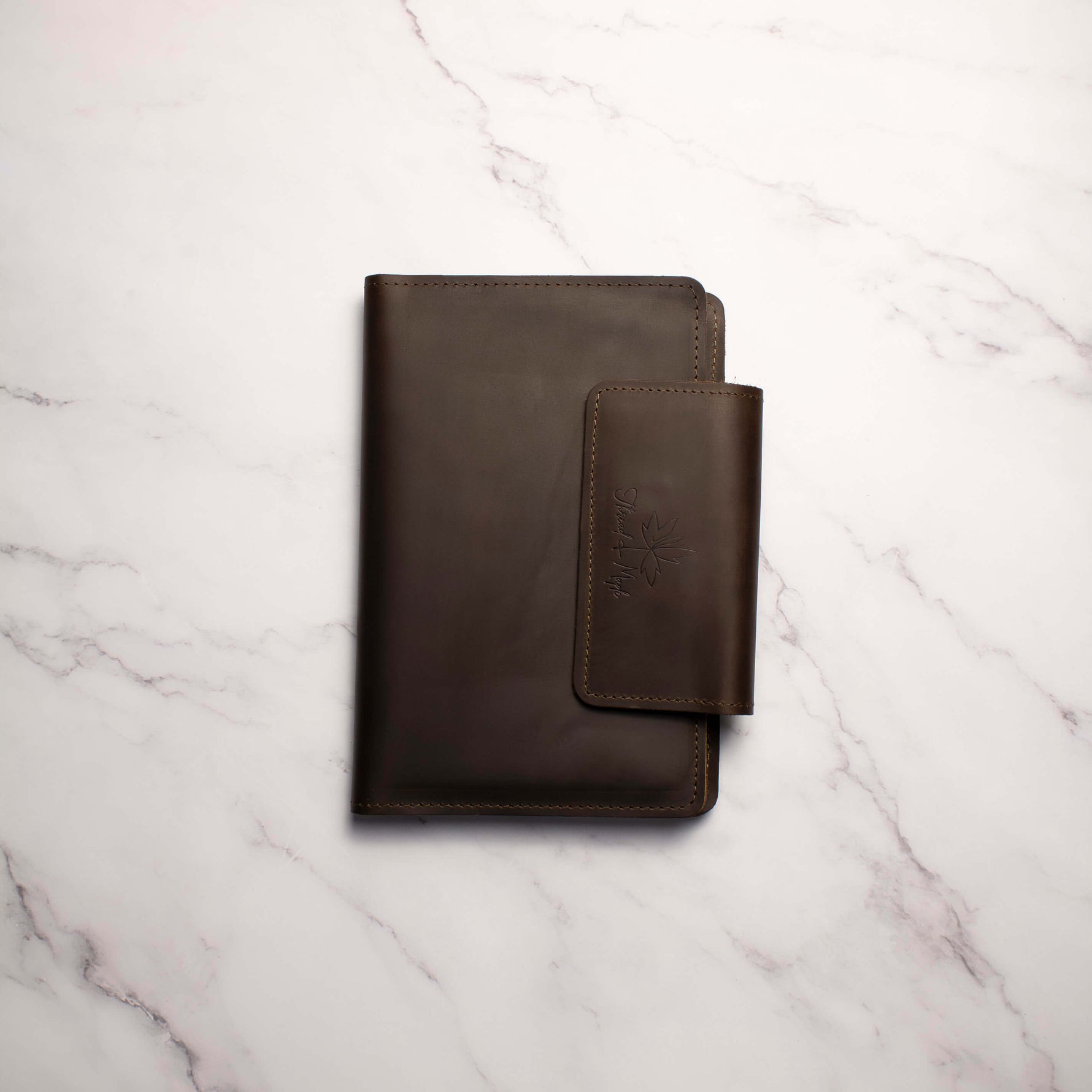 Dark brown leather notebook on a marbled white surface.