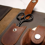 Leather case with black scissors in a stylish organizer set on a wooden surface.
