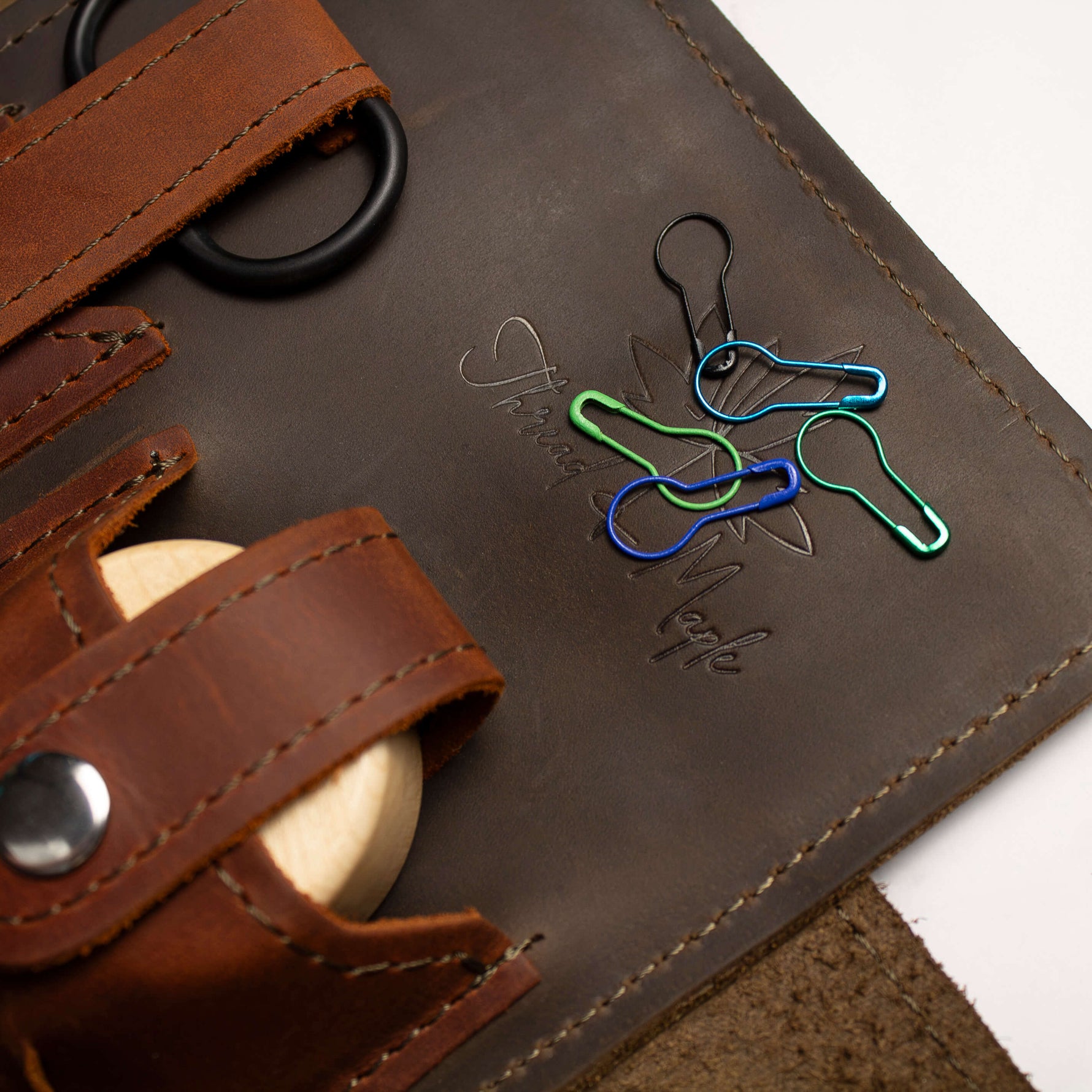Close-up of a leather toiletry bag with colorful key-shaped clips laying on it.