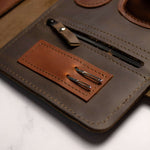 Leather pen case with pocket clips and fountain pen on a marble surface, close-up view.