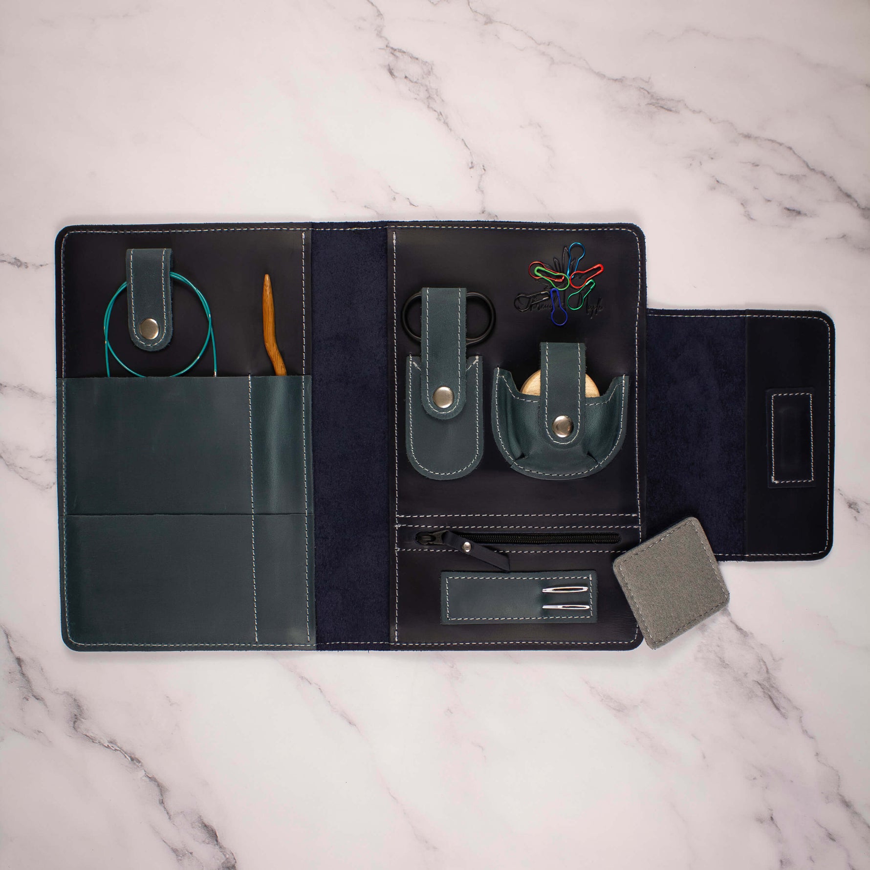 Travel organizer case open displaying storage compartments on a marble surface.