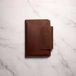 Brown leather passport holder on white marble background