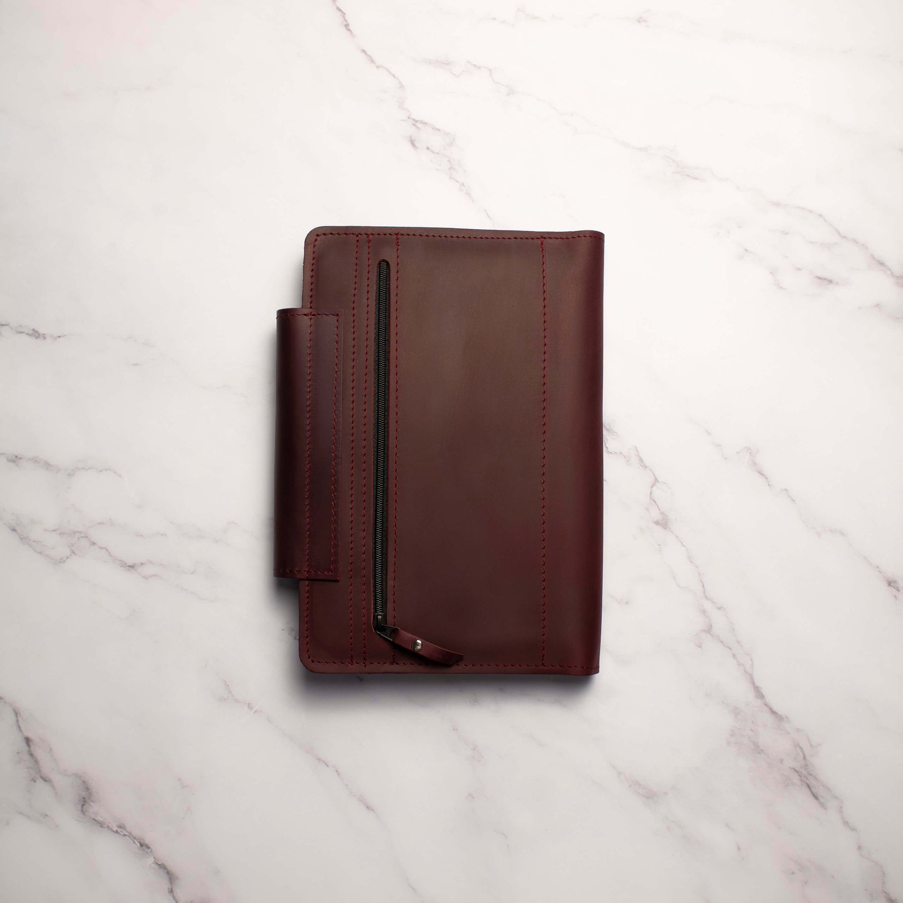 Brown leather wallet with a zipper on a marble surface
