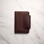 Brown leather wallet on a white marble surface.