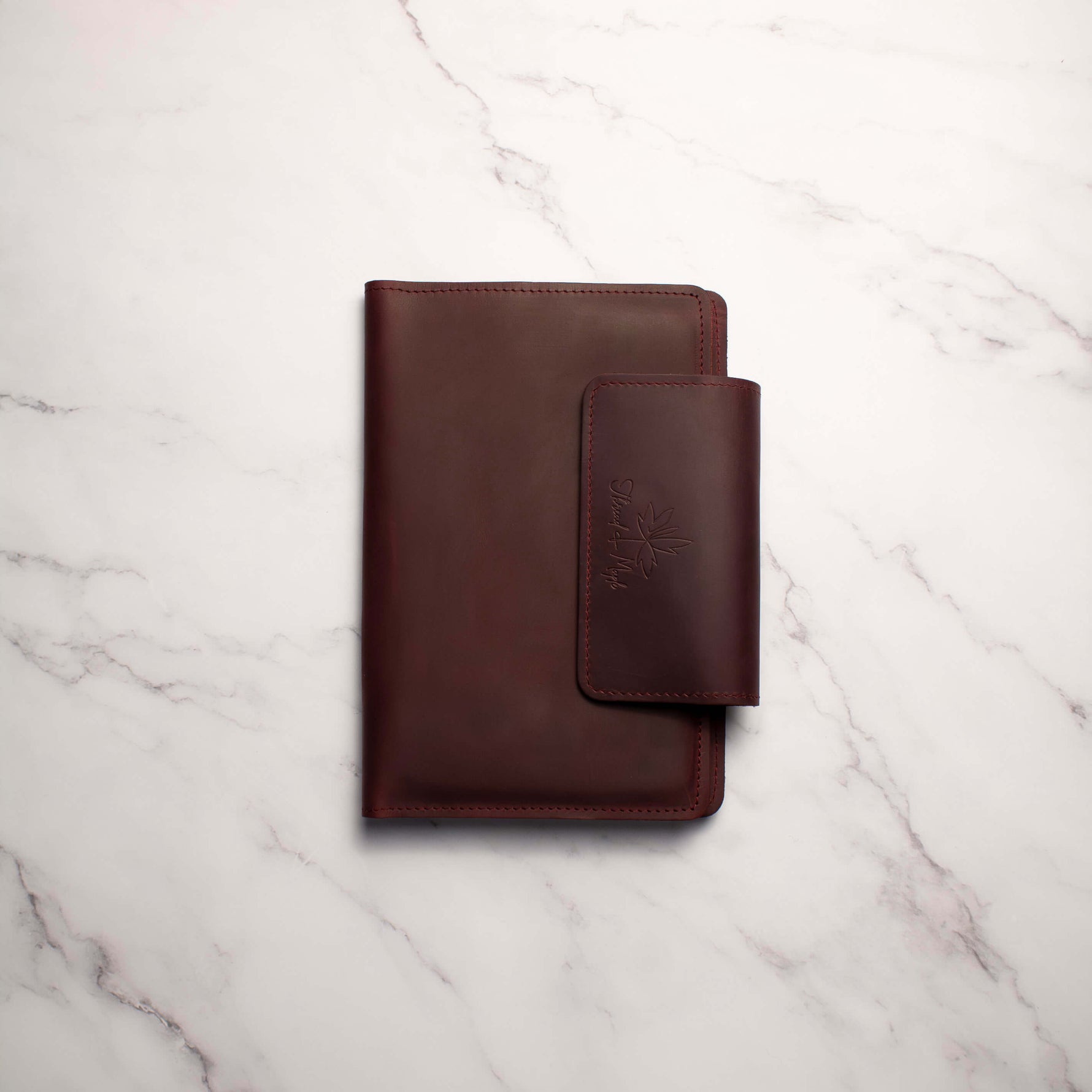 Brown leather wallet on a white marble surface.